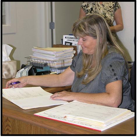 A woman sits a desk filing out paperwork